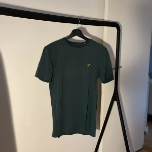 Grön t-shirt från Lyle & Scott - Säljer en snygg mörk grön t-shirt från Lyle & Scott i storlek M. T-shirten är gjord i mjuk bomull.  Har flera av dessa t-shirts i andra färger i min profil. Nypris: 300kr