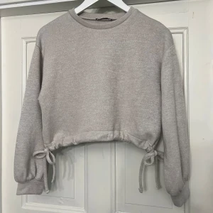 Beige croppad tröja med knyt - Beige tröja med knytning på sidorna. Storlek S från Zara. Väldigt bra skick. 
