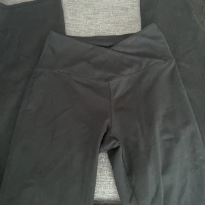 Svarta byxor från Danskin - Säljer ett par svarta byxor från Danskin i storlek S. De är superbekväma och perfekta för både träning och vardag. Byxorna har en hög midja och en rak passform som ger en snygg siluett. Materialet är mjukt och stretchigt, vilket gör dem idealiska för yoga eller andra aktiviteter. Passa på att fynda dessa mångsidiga byxor!