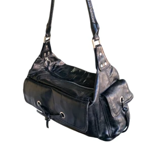 Svart axelväska i skinn - Säljer en snygg svart axelväska. Den har en cool design med dragkedja och små fickor på sidorna. Den har även innerfickor. (Notera att det finns en liten skada på en av innerfickorna men som går att laga) det är inget som syns utifrån❤️