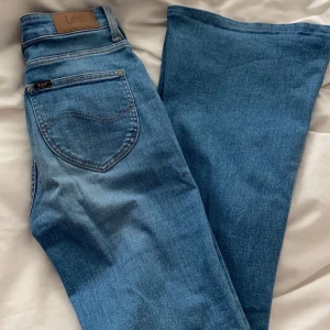Blå jeans från Lee - Säljer ett par snygga blå jeans från Lee i mycket bra skick. De är mid waist och är bootcut. I storlek xs/s W24/L31. Nypris 1200kr