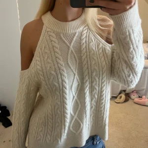 Vit stickad offshoulder tröja från Mango - Säljer en superfin vit stickad tröja från Mango. Den har en unik offshoulder-design och ett snyggt flätmönster. Perfekt för höst och vinter, och den är både mysig och stilren. Passar perfekt till jeans eller kjol för en chic look!