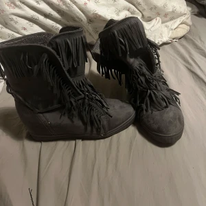 Grå boots med fransar - Säljer ett par grå boots i mocka med coola fransdetaljer. De har en dold kilklack och snörning framtill. Isabell marant liknande