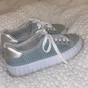 Grå/blåa sneakers från Graceland - Säljer ett par grå sneakers från Graceland i bra skick. Skorna har en perforerad design med vita snören och en vit sula. Perfekta för vår och sommar! 🩶  