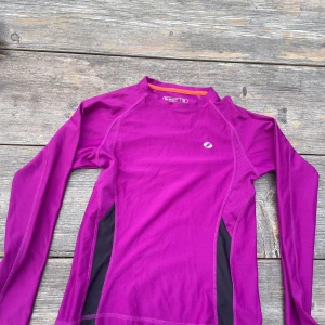 Lila långärmad träningströja från SOCk - Säljer en snygg lila långärmad träningströja med  svarta detaljer på sidorna. Den är i väldigt bra skick, från soc och kostar endast 20 kr. 