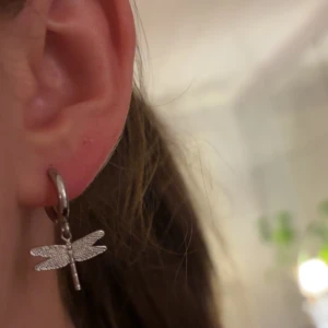 Silverörhängen med trollslända - Säljer ett par superfina silverörhängen med en hängande trollslända. Perfekta för att ge en touch av naturinspirerad elegans till din outfit. De är i mycket bra skick och passar både till vardags och fest. (De saniteras såklart före frakt)