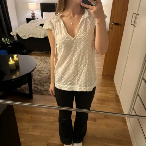 Vit blus med knyt och spetsdetaljer - Säljer en söt vit blus med spetsdetaljer och knytning vid halsen. Blusen har korta ärmar och en luftig passform. Den är i mycket bra skick och passar både till vardags och festliga tillfällen. 💗
