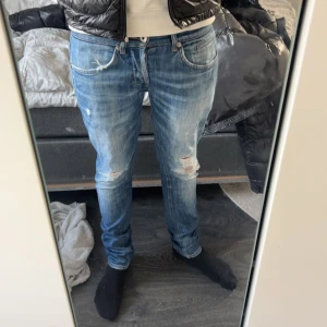 Dondup jeans - Säljer ett par snygga blå jeans med slitningar på knäna.  Från dondup george . storlek 30,, perfekt för en avslappnad stil. Jeansen är i bra skick och passar både till vardags och fest. Skicka ett meddelande vid intresse!