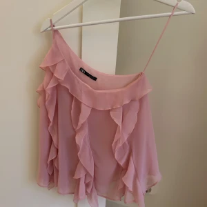 Rosa linne från Zara - Säljer ett supersött rosa linne från Zara . Det är ärmlöst med volangdetaljer som är superfint. Perfekt för sommarens fester eller en dag på stan. Passar bra till både jeans och kjol!