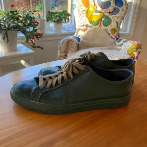  Sneakers från Filippa K - Säljer ett par stilrena svarta sneakers från Filippa K i skinn. De har en klassisk design med snörning och är i bra skick. Perfekta för både vardag och festliga tillfällen. Tillverkade i Portugal. Passar även i 43. Finns några skrapor som syns på bilderna