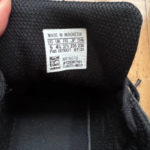 Svarta sneakers från Adidas - Säljer ett par klassiska svarta Adidas sneakers i bra skick. De har den ikoniska snäckformade tån och tre ränder på sidan. Perfekta för vardagsbruk och ger en stilren look. Tillverkade i syntetmaterial med snörning för bästa passform.