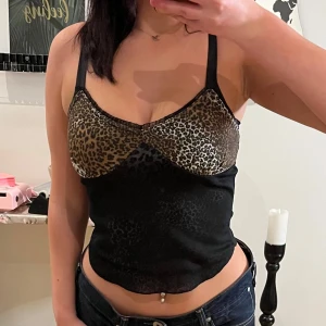 Leopardmönstrad topp från B.Young - Snygg leopardmönstrad topp från B.Young i storlek S. Toppen har smala axelband och en tight passform. Den är i ett mjukt och stretchigt material som sitter bekvämt. Leopardmönstret ger en trendig touch och den svarta basen gör den lätt att matcha med andra plagg.