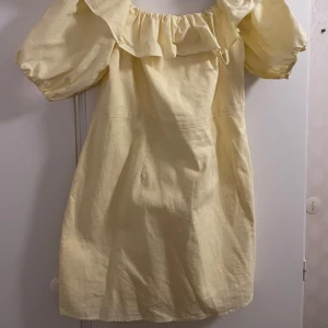 Gul klänning från H&M - Säljer en söt gul klänning från H&M i storlek L. Den har puffiga kortärmar och en volangdetalj runt halsen som ger en romantisk touch. Perfekt för vår och sommar! 🌼