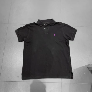 Svart pikétröja från Ralph Lauren - Säljer en klassisk svart pikétröja från Ralph Lauren i bra skick, den har tecken på använding men har varit bra omhändetagen! Saknar lapp innut i tröjan! Pris är diskuterbart! 
