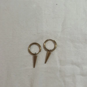 Guldörhängen med spetsig detalj - Säljer ett par coola guldörhängen med en spetsig hängande detalj. Perfekta för att ge din outfit en edgy touch! De är i mycket bra skick och passar både till vardags och fest. 🖤
