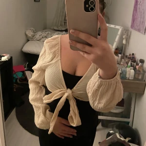 Beige knytblus från Shein - Säljer en superfin beige blus från Shein i storlek S. Den har långa ärmar och en snygg knytning framtill som ger en sötlook. Perfekt för både vardag och fest! Materialet är lätt och luftigt, vilket gör den bekväm att bära hela dagen.