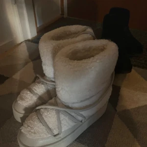 Vita fluffiga skor - Supermysiga inukii liknande  vita boots i syntetmaterial med fluffig pälsdetalj. Perfekta för vintern. De har en hög sula och snörning. Passar perfekt för kalla dagar när du vill hålla fötterna varma! De är en liten fläck på sulan (sista bilden) jag tror att fläcken borde försvinna om man bara försöker tvätta dom, då fläcken inte är så stor så ser man den endån knappt😊