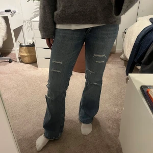 Blå jeans med slitningar - Säljer dessa snygga blå jeans med slitningar. De har en bootcut-stil.  Jeansen är i bra skick!!💕