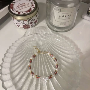 Färgglatt pärlarmband med rosett - Säljer ett supergulligt armband med färgglada pärlor och en söt rosett i mitten. Armbandet har en justerbar kedja i guld för perfekt passform. Perfekt för att liva upp vilken outfit som helst! ✨