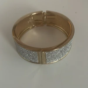 Glittrigt guldarmband Ny - Snyggt och stilrent armband i guld med en glittrig silveryta.Ny aldrig använt. Perfekt för att ge lite extra bling till din outfit. Armbandet har en enkel låsmekanism och är i mycket bra skick. Passar perfekt till festliga tillfällen eller när du bara vill känna dig extra glamorös.
