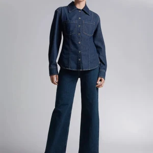 Mörkblå jeansskjorta - Snygg mörkblå jeansskjorta i nytt skick med klassisk krage och knappar framtill. Skjortan har två bröstfickor och långa ärmar, perfekt för en avslappnad stil. Passar bra till både vardag och fest!