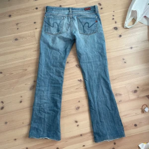Blå bootcut jeans - Säljer ett par snygga blå bootcut jeans i bra skick. De har en låg midja och klassisk femficksdesign. Perfekta för en avslappnad stil