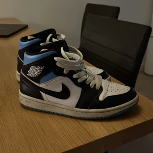 Nike Air Jordans i svart och blått - Säljer ett par Nike Air Jordans i svart, blått och vitt. Skorna har en klassisk hög modell med snörning. De är i bra skick med lite slitage på sulan