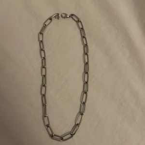 Silverfärgat halsband  - Snyggt och trendigt halsband i silverfärg med stora, rektangulära länkar. Perfekt för att ge en edgy touch till vilken outfit som helst. Passar både till vardags och fest. Lätt att matcha med andra smycken.