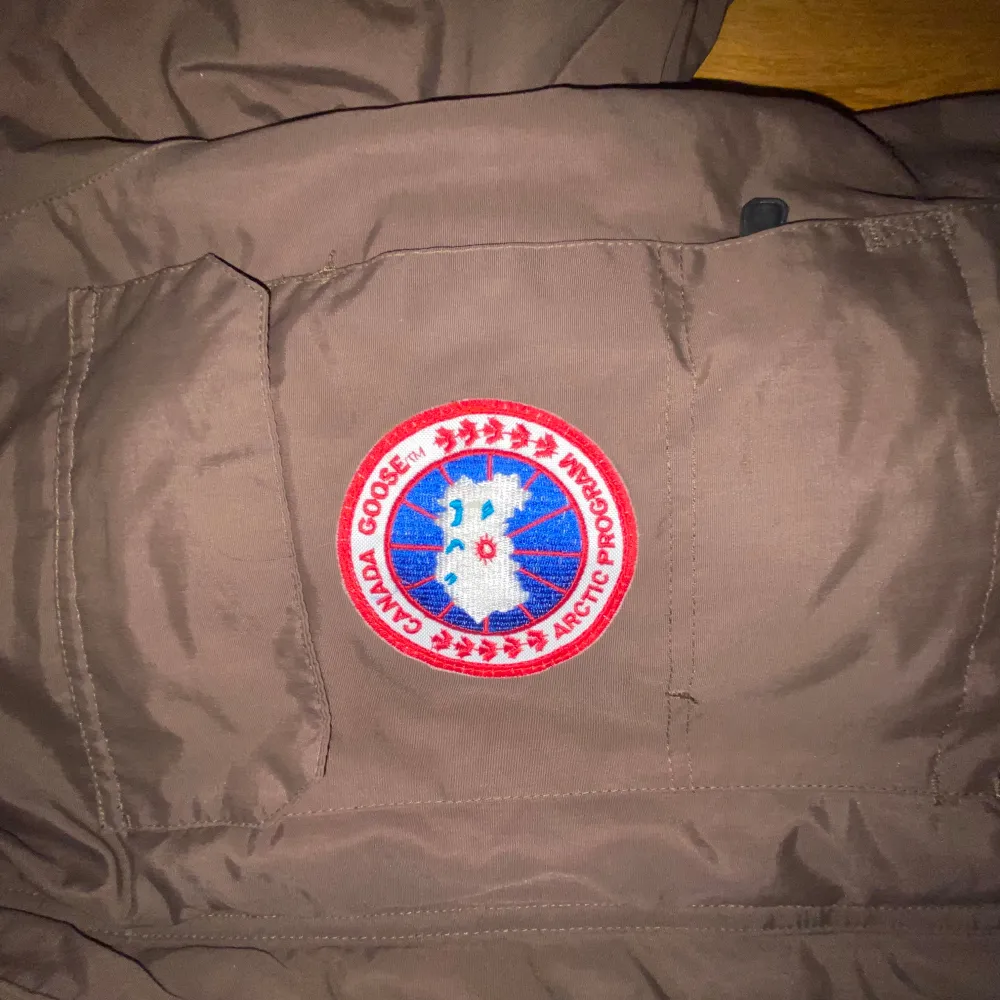 Säljer en brun parkajacka från Canada Goose i mycket bra skick. Jackan är perfekt för vintern med sitt varma dunfoder och har en klassisk design med huva och flera praktiska fickor. Den är tillverkad i polyester och bomull med nylonfoder. Perfekt för kalla dagar! ❄️. Jackor.