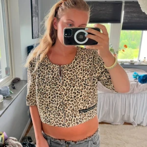 Snygg topp🐆 - Säljer en supercool leopardmönstrad topp. Den är kortärmad och croppad med en dragkedja framtill och en snygg detalj med svarta kanter på fickan. Perfekt för en utekväll eller när du vill sticka ut lite extra. 🐆✨Man kan även ha den som en jacka på svalare sommarkvällar! 