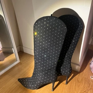 Svarta stövlar med glittriga detaljer - Snygga svarta stövlar med spetsig tå och klack. De är täckta med små glittriga stenar som ger en festlig look. Perfekta för en utekväll eller fest!❤️ använt en gång 😍 7,5cm i klackhöjd nypris 700kr