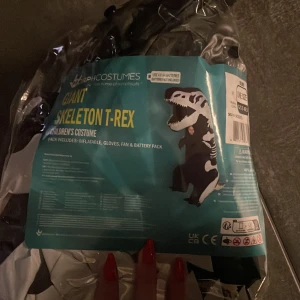 Uppblåsbar T-Rex skelettdräkt  - Cool uppblåsbar T-Rex skelettdräkt från MorphCostumes. Perfekt för halloween eller maskerad! Dräkten är svart och vit med ett skelettmönster och inkluderar fläkt och handskar. Kräver 4 AA-batterier (ingår ej). Oanvänd därav priset 