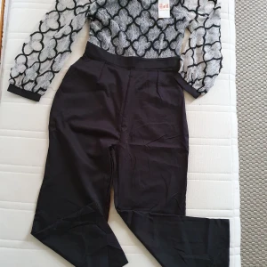 Svart och vit spetsklänning från H&H - Snygg svart och vit klänning från H&H med ett unikt spetsmönster. Klänningen har långa ärmar och en dragkedja i ryggen. Perfekt för festliga tillfällen! 🖤🤍