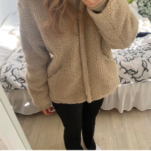 Beige teddyjacka - Mysig beige teddyjacka perfekt för kyliga dagar. Den har en normal passform och långa ärmar, vilket gör den superbekväm och varm. Perfekt för höst och vinter, och den funkar lika bra till vardags som till en chill kväll med vänner. 🧥✨