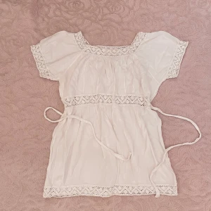 Vit tröja med spetsdetaljer🐇 - Jätte söt vit tröja med fina spetsdetaljer. Tröjan har korta ärmar och ett knytband i midjan för en justerbar passform. Är inte säker på märket eller storleken men den passar nog storlek S och är i väldigt gott skick!🎀