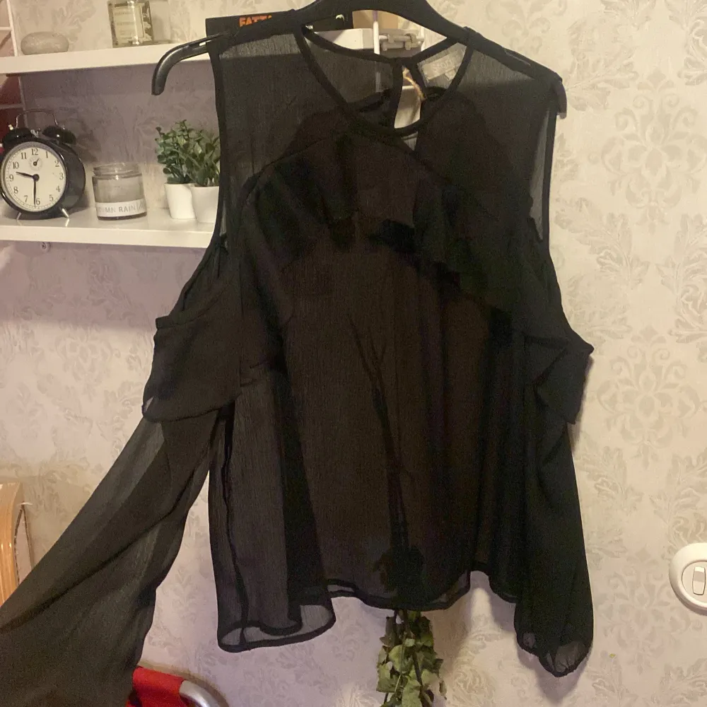 Säljer en elegant svart blus från & Other Stories i storlek M. Blusen har långa ärmar och en luftig, transparent design med volangdetaljer. Perfekt för en kväll ute eller en festlig tillställning. 🖤. Toppar.