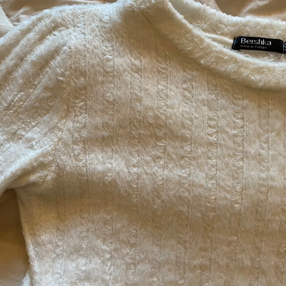 En vit t-shirt ifrån Bershka i storlek S. Är i ett lite fluffigt material som syns på bilderna och ärmarna är lite längre och en tajtare modell på tröjan, samt lite kortare i längden på modellen men passar bra på mig som är 170. Är använd några gånger men i ett fint skick.. T-shirts.