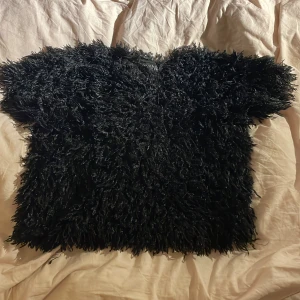 Svart fluffig topp från XOXO Friends - Säljer en supercool svart fluffig topp från XOXO Friends. Den är perfekt för att sticka ut på festen med sin unika textur. Toppen har korta ärmar och är i mycket bra skick. Passar perfekt för en trendig look! 🖤