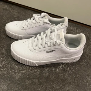 Vita sneakers från Puma - Säljer ett par snygga vita sneakers från Puma i nytt skick. De har en klassisk design med snörning och en bekväm passform. Perfekta för både vardag och träning. Skorna är i storlek dam 37 och har en stilren look som passar till det mesta. 🏃‍♀️