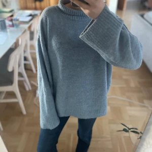 Grå stickad tröja från ICHI - Mysig grå stickad tröja från ICHI i storlek XL (Den är inte så stor utan funkar att ha som lite oversize). Perfekt för kyliga dagar med sin bekväma passform och långa ärmar. Tröjan har en ribbad kant vid ärmslut och nederkant, vilket ger en stilren look. Passar både till vardags och lite finare tillfällen.