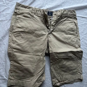 Beige shorts från Morris - Säljer ett par snygga beige shorts från Morris i bra skick. De har en klassisk design med knappar och dragkedja framtill. Perfekta för sommaren med sin bekväma passform och stilrena look. Passar både till vardags och lite finare tillfällen. Storleken står inte i byxorna men har jämfört med ett annat par som är 34 och de är lika stora. Men ta hänsyn till att de kanske inte är exakt.