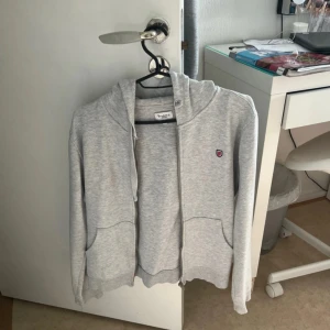 Grå hoodie från Bondelid - Säljer en grå hoodie från Bondelid i bra skick. Den har en dragkedja framtill och en liten logga på bröstet. Perfekt för en avslappnad stil och passar till de flesta tillfällen. Supermjuk och bekväm!