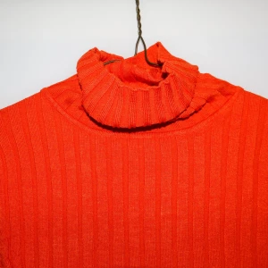 Orange ribbad polotröja - Säljer en snygg och färgstark orange polotröja med ribbad design. Perfekt för att liva upp garderoben i höst och vinter. Tröjan har långa ärmar och en mysig polokrage som håller dig varm. Passar både till vardags och festliga tillfällen. 🧡