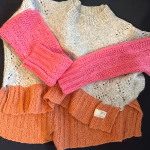 Odd Molly- Färgglad stickad tröja med hjärtmönster - Superfin stickad tröja från Odd Molly i grått, rosa och orange. Den har ett gulligt hjärtmönster på ryggen och är gjord av bl a mjuk merinoull. Perfekt för höst och vinter med sina långa ärmar och mysiga känsla. En unik och färgglad tröja som verkligen sticker ut!