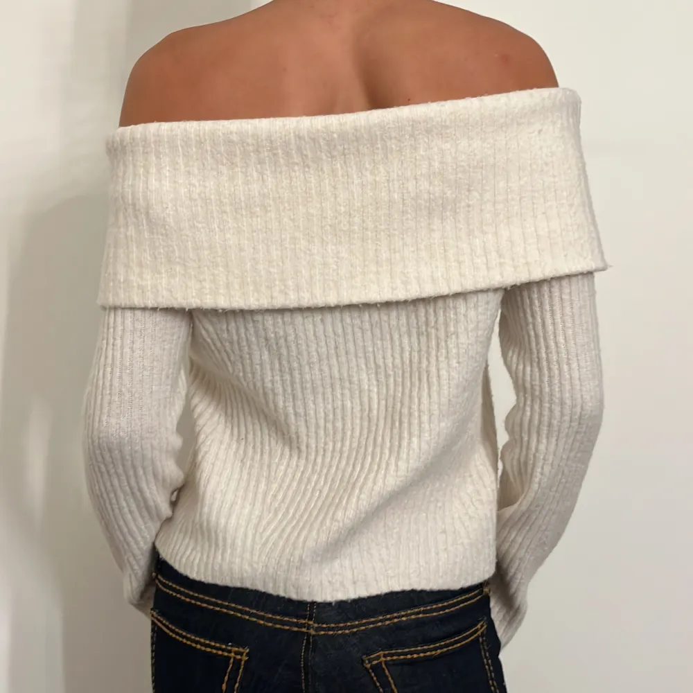 Säljer en superfin vit offshoulder tröja i ribbat material. Den har långa ärmar och en snygg, bred krage som ger en elegant look. Perfekt för både höst och vår när du vill ha något stilrent och bekvämt. Passar bra till jeans eller kjol för en chic outfit!. Tröjor & Koftor.