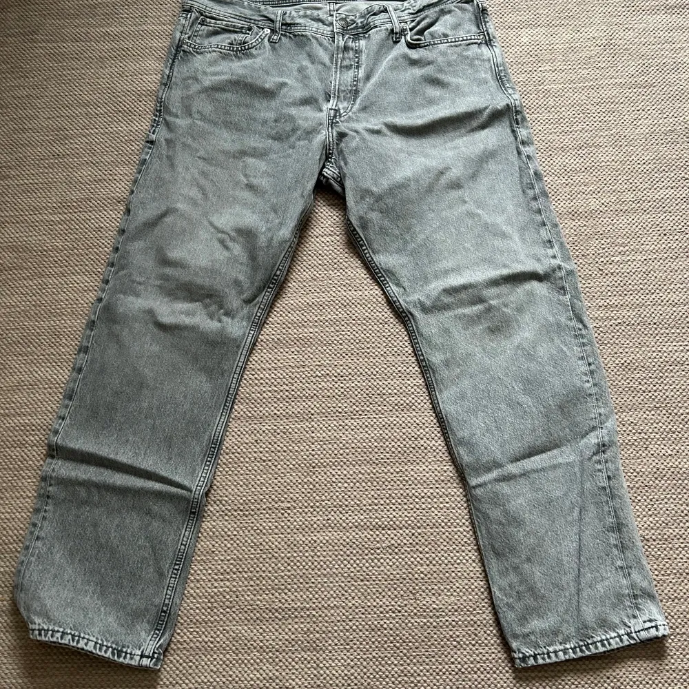 Säljer ett par grå jeans från Jack & Jones i storlek 38/32. De är i bra skick och gjorda av 100% bomull. Perfekta för en casual look med en straight passform. Passar bra till både vardag och fest. Sköna och stilrena, ett måste i garderoben!. Jeans & Byxor.