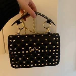 Svart väska med guldiga nitar  - Aldrig använd. 23x8 har jag för mig. Inget märke 