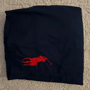 Marinblå badbyxor från Polo Ralph Lauren - Snygga marinblå badbyxor från Ralph Lauren med en stor röd broderad logotyp! 