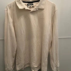 Beige pikétröja från Pierre Cardin - Snygg och bekväm beige pikétröja från Pierre Cardin i ekologisk bomull. Tröjan har långa ärmar och en klassisk krage. I storlek M men passar S också. Skicket är 9/10 och är använd 2 gånger