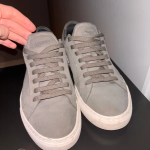 Grå sneakers från Garment Project - Snygga grå sneakers från Garment Project med snörning och vit sula. Perfekta för en stilren och avslappnad look.